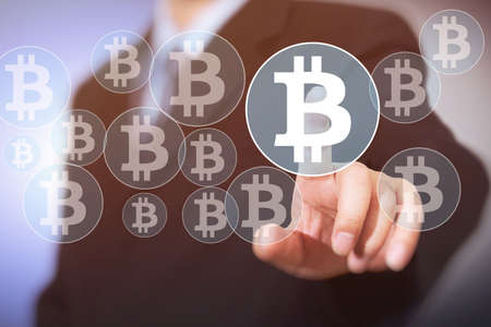 Bitcoin button on virtual interface displaying, businessman touching the currency symbolの写真素材