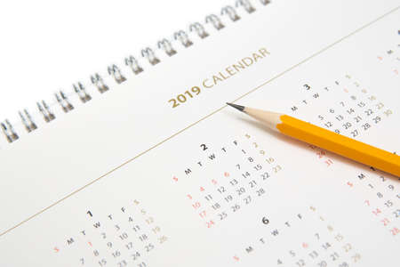 Desk calendar and yellow pencil on white background.の写真素材