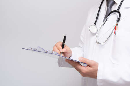 Close up of doctors hands writing on medical chart.の写真素材