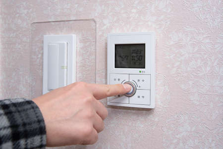 A male hand adjusting the room temperature in winter.の写真素材