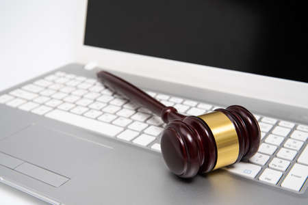 Wooden judge gavel on a silver laptop computer, cyber law or online auction concept.の写真素材
