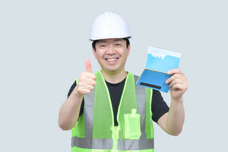 A middle-aged Asian engineer holding a bank passbook in his hand on a gray background.の写真素材