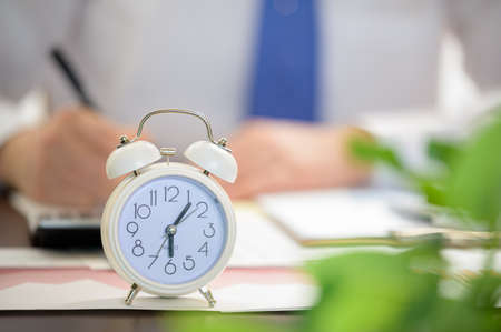 Working Businessman and White Alarm Clock. Work Time concept.の写真素材