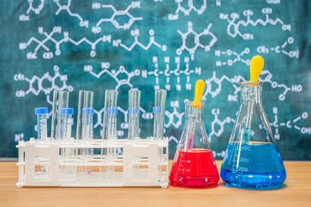 Laboratory glassware with blackboard background with various chemical formulas.の写真素材