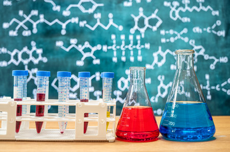 Laboratory glassware with blackboard background with various chemical formulas.の写真素材