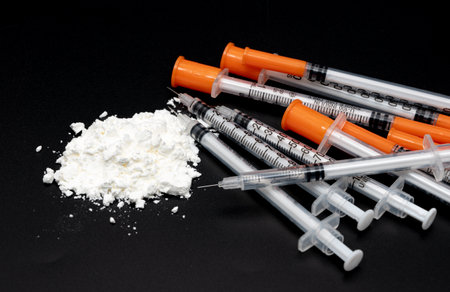 Drug crime concept with white powder and disposable syringe on black backgroundの写真素材
