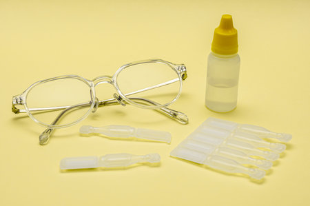 Glasses and disposable eye drops isolated on yellow backgroundの写真素材