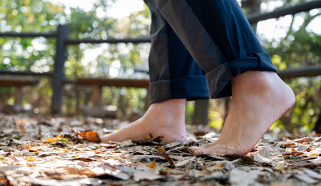 A man walking barefoot on a fallen leafy road. Healthy lifestyle conceptの写真素材
