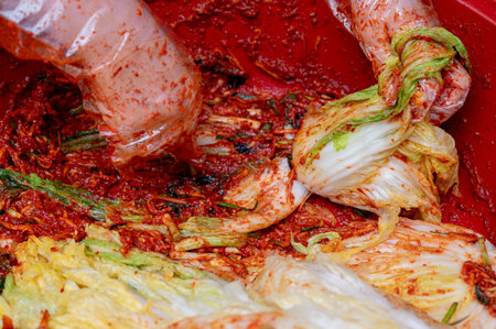 The process of making a traditional Korean dish, kimchi. Close-up of a woman's hand making cabbage kimchi by adding various seasonings to salted cabbageの写真素材