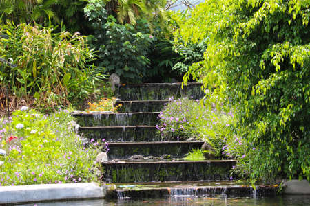 A waterfall cascading over steps in a flower garden