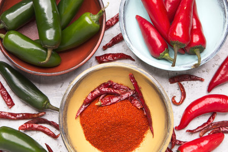 Various spicy peppers and dried peppers on the bowls and on the countertop.
