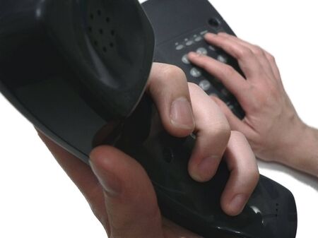 hands holding receiver and dialing on telephoneの写真素材