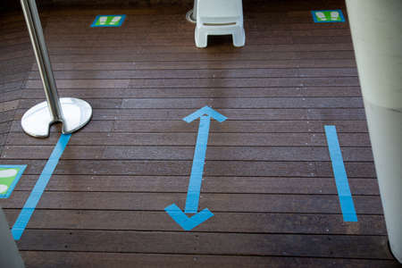 Blue arrow tape on the floor to indicate distance. Social distance sign for  infection control.の写真素材