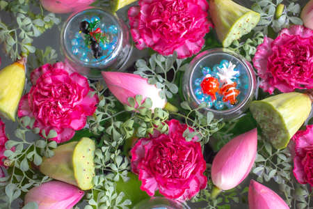 Flower arrangements of lotus and carnations. Ornaments made of glass floating on water.