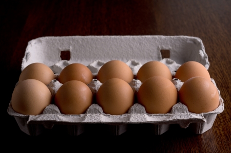 eggs in a paper on a wooden tray, dark brown tableの写真素材