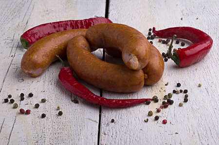smoked sausage, peppercorns, red hot chili pepper on old wooden table