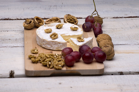 blue cheese, walnuts, grapes, on a chopping board on an old tableの写真素材