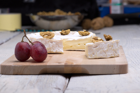 blue cheese, walnuts, grapes, on a chopping board on an old tableの写真素材