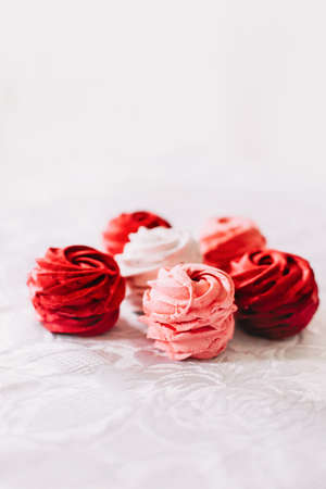 Red, pink and white zephyr on white background. Marshmallows on white tableの写真素材
