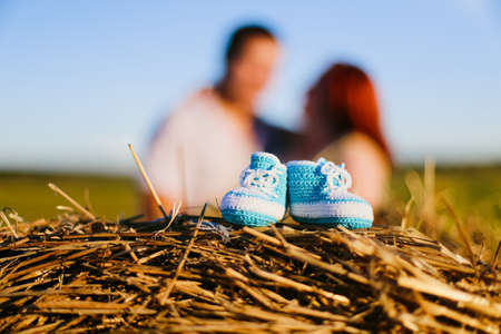 Knitted baby booties and pregnant couple in the fieldの写真素材