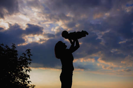 Mother holding a baby on a sky backgroundの写真素材