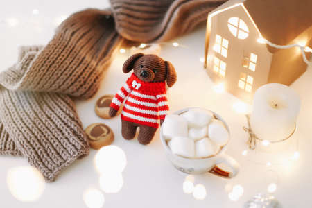 New year and christmas background with symbol of the year dog puppy toy with a cup of coffee and candles on white backgroundの写真素材