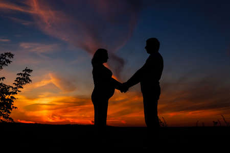 Mother and father waiting for a baby on a sky background. Happy family. Pregnant womanの写真素材