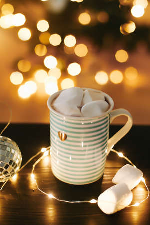 Christmas coffee cup with marshmallows on the background of New Year's lights and decorationsの写真素材