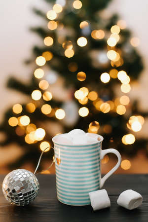 Christmas coffee cup with marshmallows on the background of New Year's lights and decorations. Still life.の写真素材
