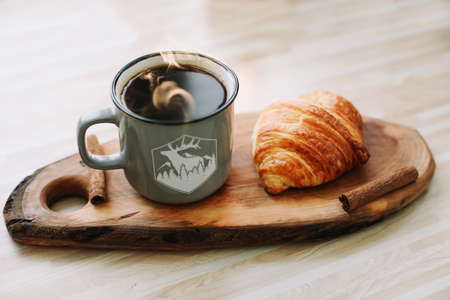 Mug of hot coffee and croissant on a wooden tray. breakfast concept. good morningの写真素材