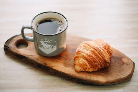 Mug of hot coffee and croissant on a wooden tray. breakfast concept. good morningの写真素材