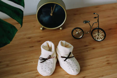 Baby's boots and toys on wooden background. Waiting for baby. white shoes for newbornの写真素材