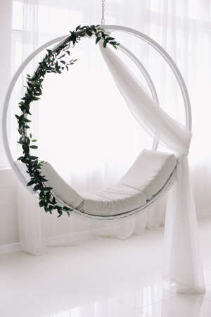 Swing decorated with flowers. White background.  White wooden swing in the studio.の写真素材