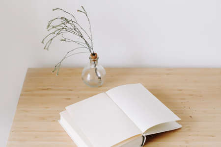 wooden desk with book and flowers. Flat lay, top view.