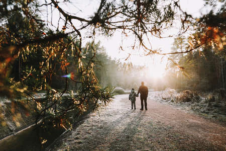 Father and son walk along the river bank. Silhouettes of people on the background of nature. Winter Christmas landscape. Winter forest on the river. Travel conceptの写真素材