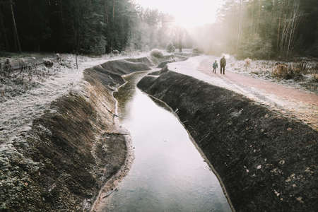 Father and son walk along the river bank. Silhouettes of people on the background of nature. Winter Christmas landscape. Winter forest on the river. Travel conceptの写真素材