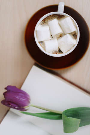 Fresh tulips with book and cup of coffee on wooden background. Spring flowers and a cup of coffee with book, spring concept. top view. flatlayの写真素材