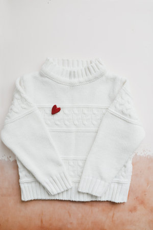 Top view white woolen sweater with a red heart. Love, romance, Valentines Day concept. Flat lay, copy spaceの写真素材