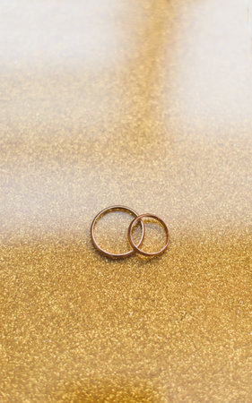 Two golden wedding rings on a golden backgroundの写真素材