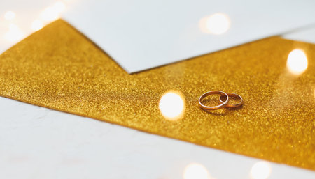 Two golden wedding rings on a golden backgroundの写真素材