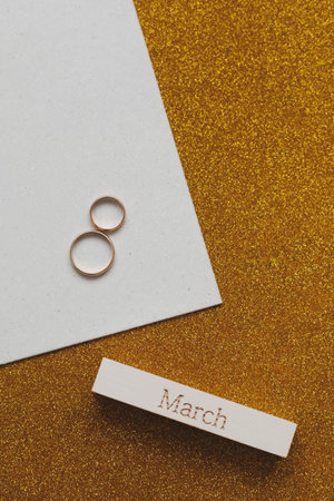 8 March, International Womens Day background with decor elements. Eight made of two gold wedding rings and word MARCH. Flat lay, top view, copy spaceの写真素材