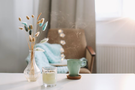 Cup of coffee and a transparent vase with dried flowers at white background