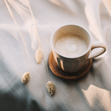 Cup of coffee with milk on beige plaid. Flat lay, top view still life morning breakfast. Comfort, cosiness and warmth concept. Photo in light pastel colorsの写真素材