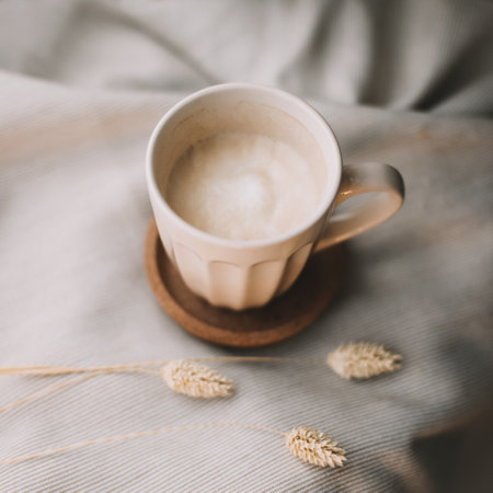 Cup of coffee with milk on beige plaid. Flat lay, top view still life morning breakfast. Comfort, cosiness and warmth concept. Photo in light pastel colorsの写真素材