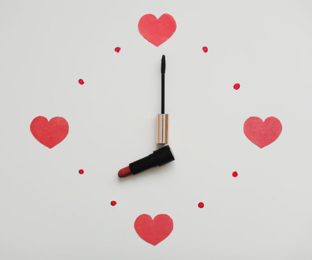 Clock face and arrows on a white background made from cosmetic products for make-up, lipstick and brush. Flat lay top view. Saint Valentines day, Womens day conceptの写真素材