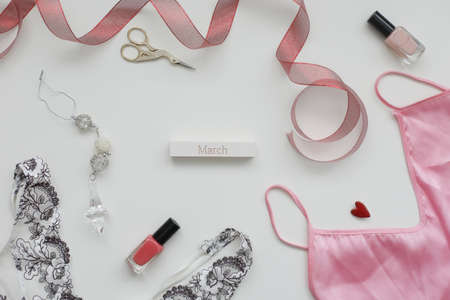 Concept Womens Day, March 8. Female underwear with a red ribbon and cosmetics on white background. Styled flat lay, top view, copy space.の写真素材