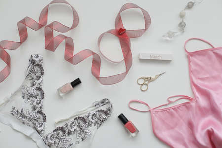 Concept Womens Day, March 8. Female underwear with a red ribbon and cosmetics on white background. Styled flat lay, top view, copy space.の写真素材