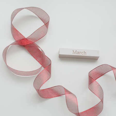 Red ribbon and word MARCH on white background. 8 March, International Womens Day concept.の写真素材