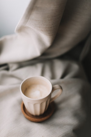 Cup of coffee with milk on beige plaid. Flat lay, top view still life morning breakfast. Comfort, cosiness and warmth concept. Photo in light pastel colorsの写真素材