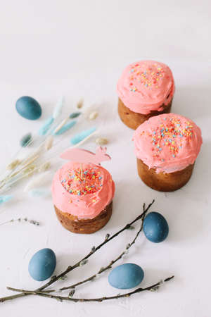 Easter cake, colorful eggs and willow branches on light backgroundの写真素材